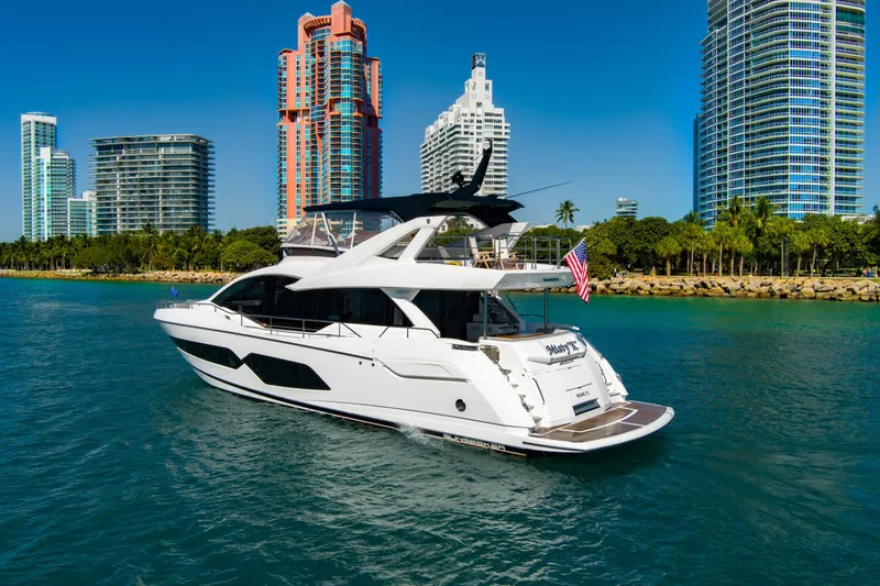 Slide: The Image of 2024 Sunseeker 76 Yacht cruising near modern city skyline and waterfront. - 7