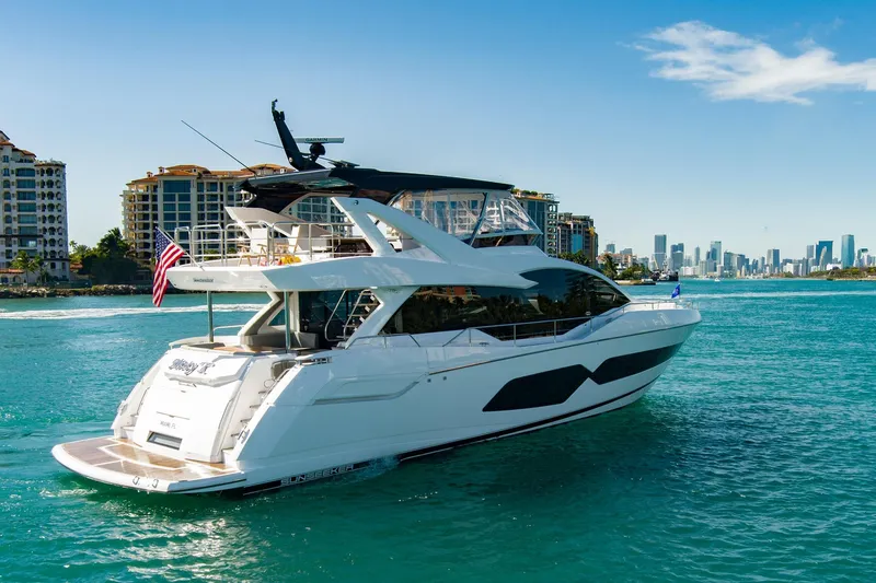 Slide: The Image of 2024 Sunseeker 76 Yacht cruising near city skyline, clear blue water, sunny day. - 8