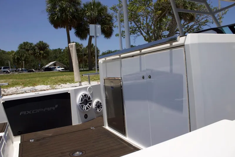 Slide: The Image of 2017 Axopar 28TT boat interior with speakers and storage, surrounded by palm trees. - 11