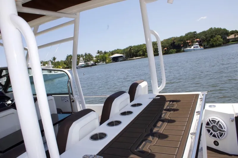 Slide: The Image of 2017 Axopar 28TT boat interior with seating and cup holders, overlooking a scenic waterway. - 6