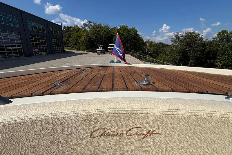 Slide: The Image of 2021 Chris-Craft Calypso 35 boat with wooden deck and flag, parked near a building. - 57