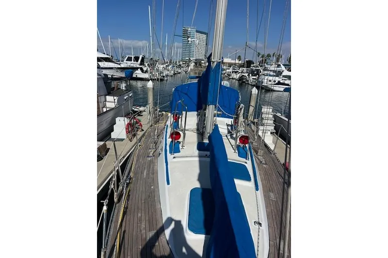 Slide: The Image of 1987 Tayana Vancouver 42 sailboat docked in a marina, featuring blue covers and clear skies. - 12