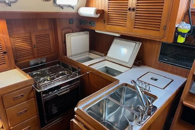 Slide: The Image of 1987 Tayana Vancouver 42 yacht kitchen with stove, sink, and wooden cabinetry. - 15