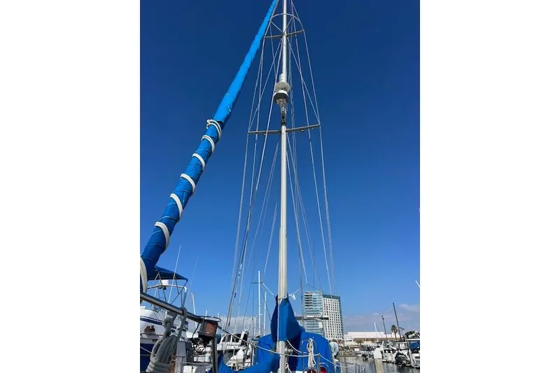 Slide: The Image of 1987 Tayana Vancouver 42 sailboat with blue sails docked at marina under clear sky. - 6