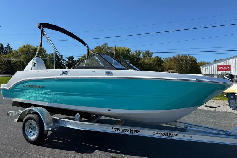 Slide: The Image of 2026 Stingray 172 DC boat on trailer, turquoise hull, sunny day, outdoor display. - 5