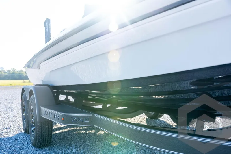 Slide: The Image of 2026 Skeeter ZXE21 boat on trailer, sunlit, gravel background. - 13