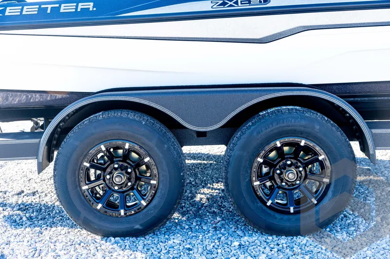 Slide: The Image of 2026 Skeeter ZXE21 boat trailer with dual black alloy wheels on gravel. - 15