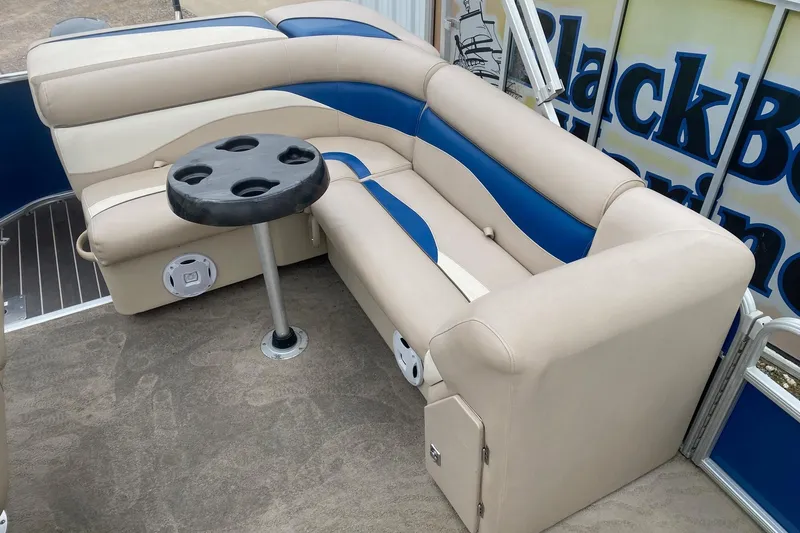Slide: The Image of 2013 Sweetwater 2286 boat interior with beige and blue seating, cup holder table. - 10
