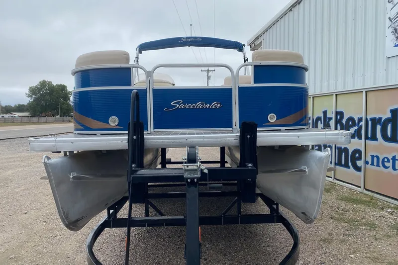 Slide: The Image of 2013 Sweetwater 2286 pontoon boat on trailer, blue and beige design, parked outdoors. - 3