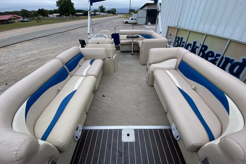 Slide: The Image of 2013 Sweetwater 2286 pontoon boat with beige and blue seating, parked near a building. - 8