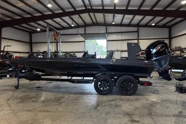 Slide: The Image of 2025 iKon VLX20 boat in a warehouse, featuring sleek black design and powerful outboard motor. - 1