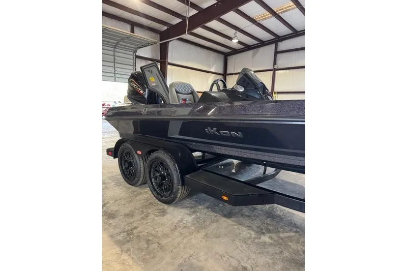 Slide: The Image of 2025 iKon VLX20 boat in a warehouse, featuring sleek black design and dual-axle trailer. - 2
