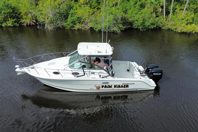 Slide: The Image of 2002 Wellcraft 290 Coastal boat on calm water, surrounded by lush greenery. - 10