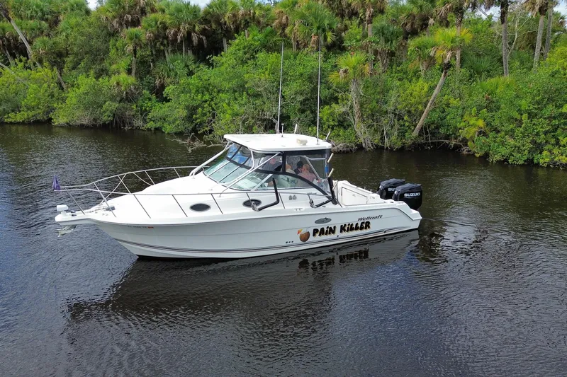 Slide: The Image of 2002 Wellcraft 290 Coastal boat on a calm river, surrounded by lush greenery. - 12