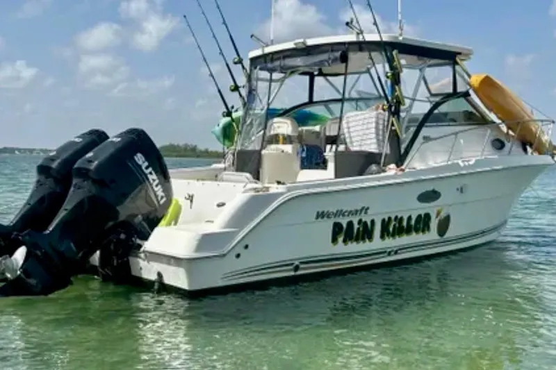 Slide: The Image of 2002 Wellcraft 290 Coastal boat named "Pain Killer" with Suzuki engines in clear water. - 13