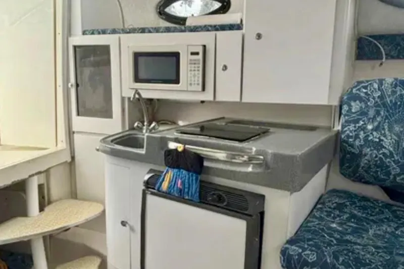 Slide: The Image of 2002 Wellcraft 290 Coastal boat interior with kitchenette, microwave, sink, and seating. - 24