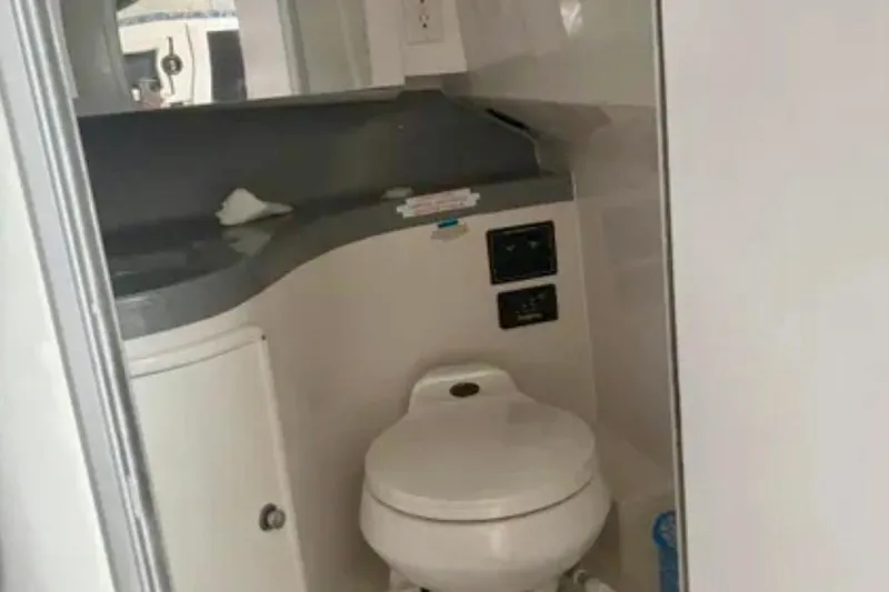 Slide: The Image of Compact bathroom in 2002 Wellcraft 290 Coastal boat, featuring a toilet and countertop. - 26