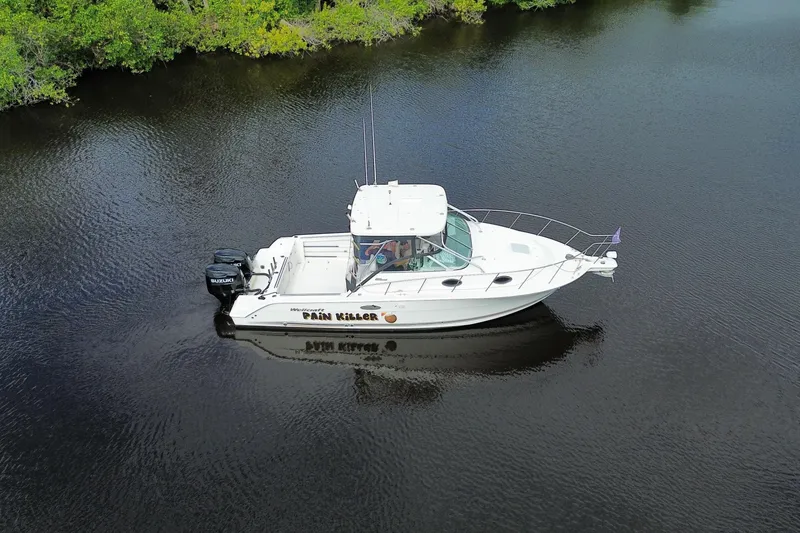 Slide: The Image of 2002 Wellcraft 290 Coastal boat on calm water, surrounded by lush greenery. - 5