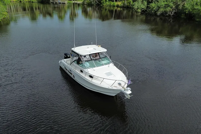 Slide: The Image of 2002 Wellcraft 290 Coastal boat cruising on a calm river surrounded by lush greenery. - 9