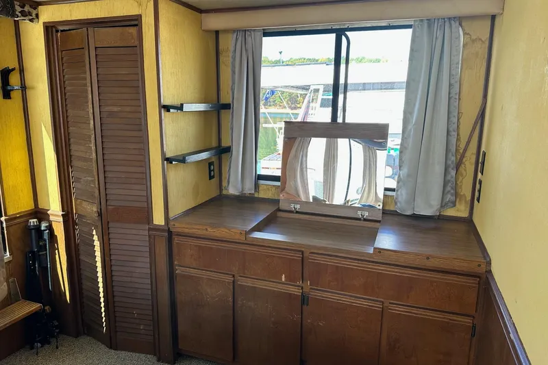 Slide: The Image of 1987 Hilburn 14x45 interior with wooden cabinets, mirror, and window view. - 10