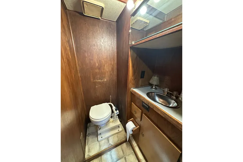 Slide: The Image of 1987 Hilburn 14x45 bathroom with wood paneling, toilet, and sink. - 13