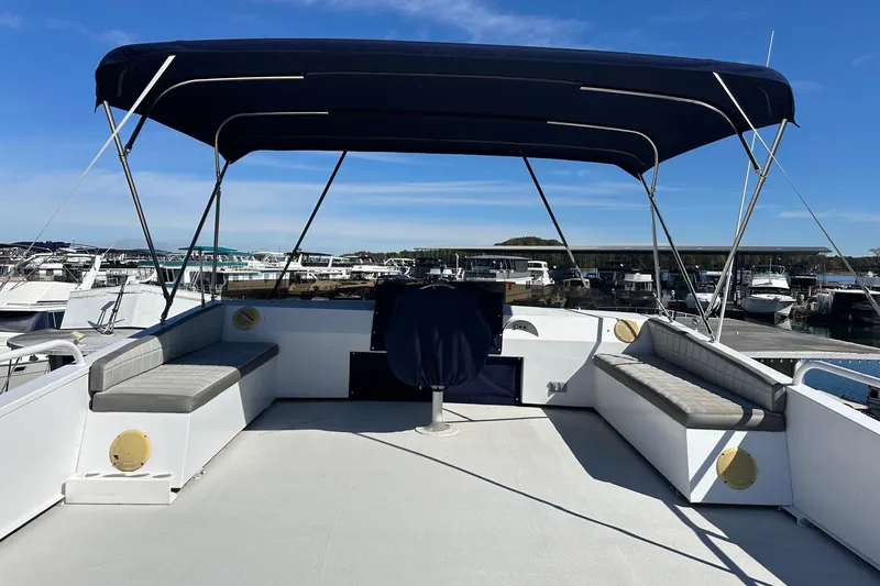 Slide: The Image of 1987 Hilburn 14x45 boat deck with canopy, docked at marina under clear blue sky. - 14