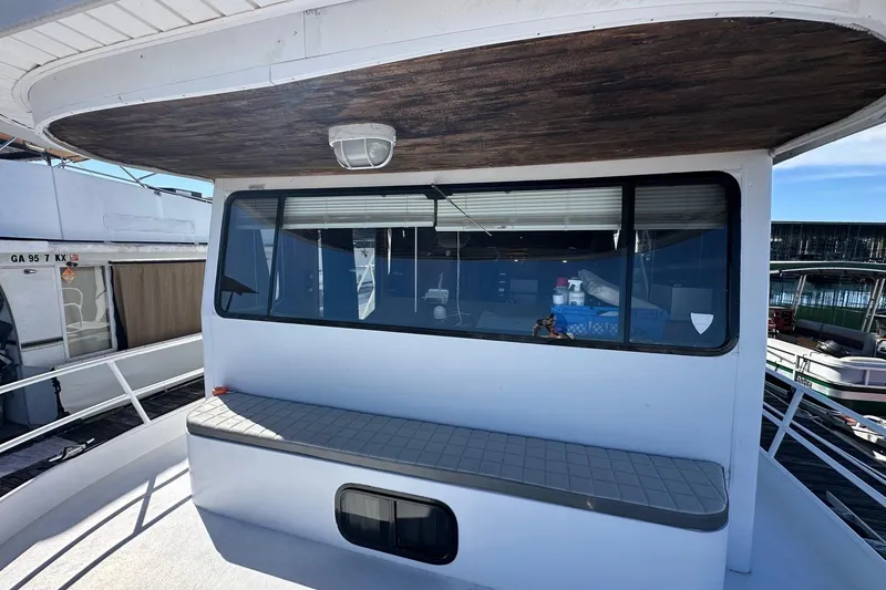 Slide: The Image of 1987 Hilburn 14x45 houseboat with exterior seating and large windows at a marina. - 2