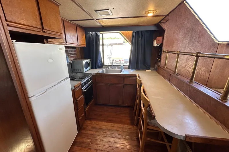Slide: The Image of 1987 Hilburn 14x45 kitchen with wooden cabinets, white fridge, and bar seating. - 8
