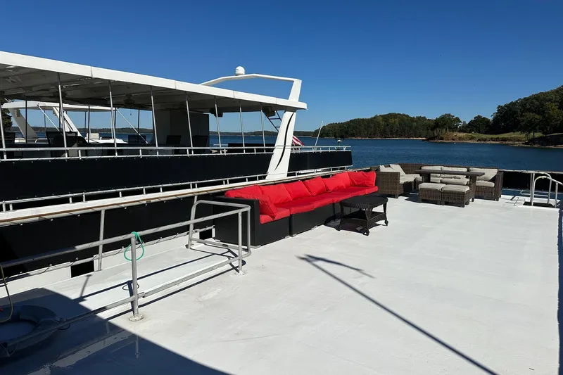 Slide: The Image of 1998 Stardust Cruisers 16x86 houseboat with spacious deck, red seating, and scenic lake view. - 13