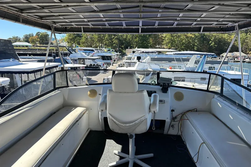 Slide: The Image of 1998 Stardust Cruisers 16x86 houseboat helm with marina view, featuring seating and navigation equipment. - 14