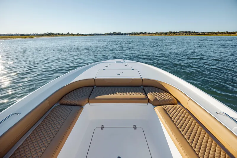 Slide: The Image of 2026 Caymas 24 HB boat with tan seating, cruising on a calm lake. - 10