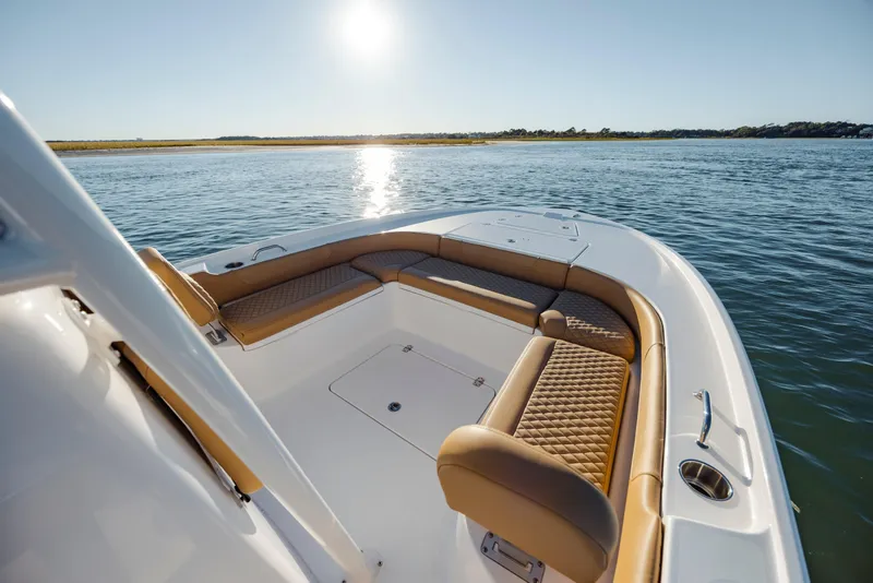 Slide: The Image of 2026 Caymas 24 HB boat interior with tan seating, on calm water under bright sun. - 12