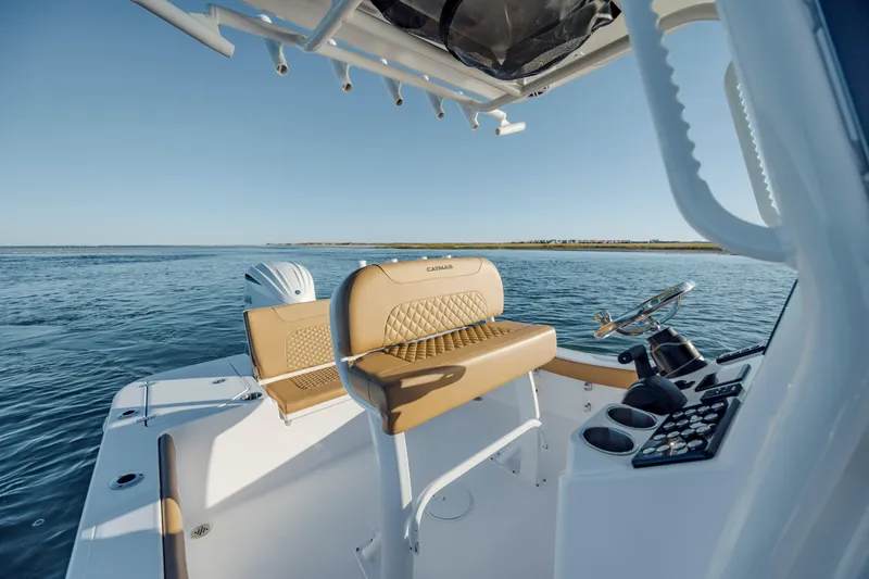 Slide: The Image of 2026 Caymas 24 HB boat interior with tan seating, steering console, and ocean view. - 16