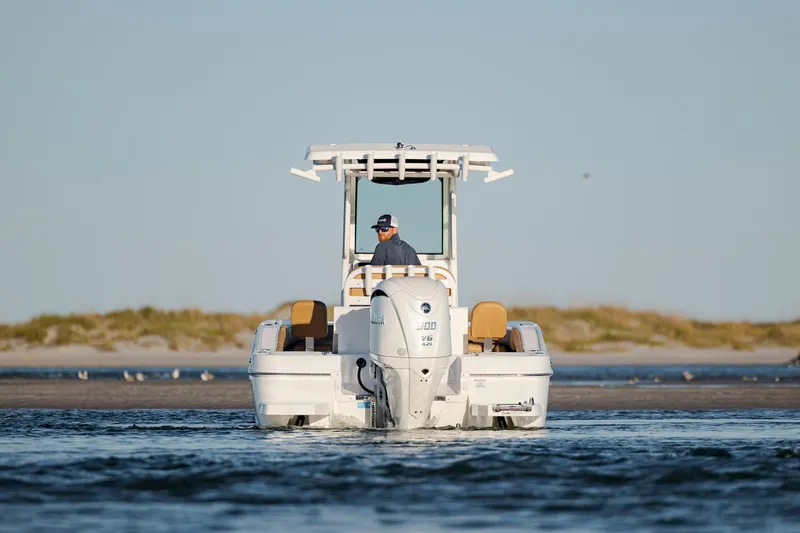 Slide: The Image of 2026 Caymas 24 HB boat cruising on calm water near a sandy shoreline. - 4