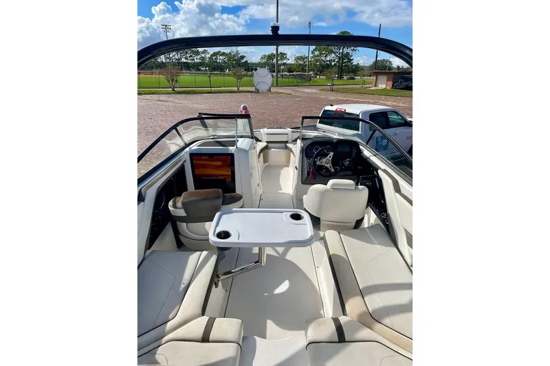 Slide: The Image of 2015 Yamaha Boats 242 Limited S interior with seating and table, parked outdoors. - 6