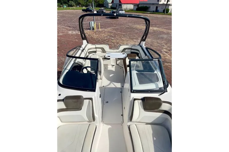 Slide: The Image of 2015 Yamaha Boats 242 Limited S interior with seating and windshield, parked on brick pavement. - 8