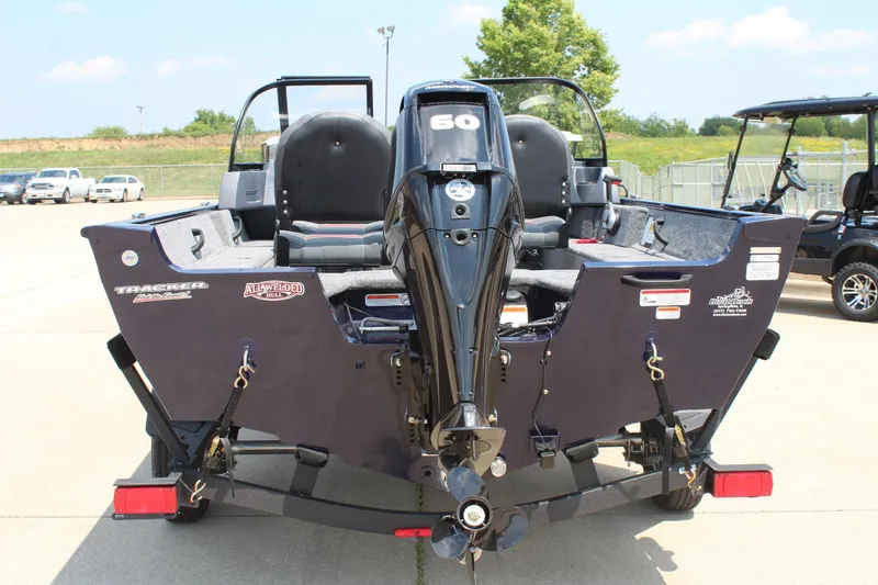 Slide: The Image of 2026 Tracker Pro Guide V-16 WT boat with outboard motor, parked outdoors. - 6