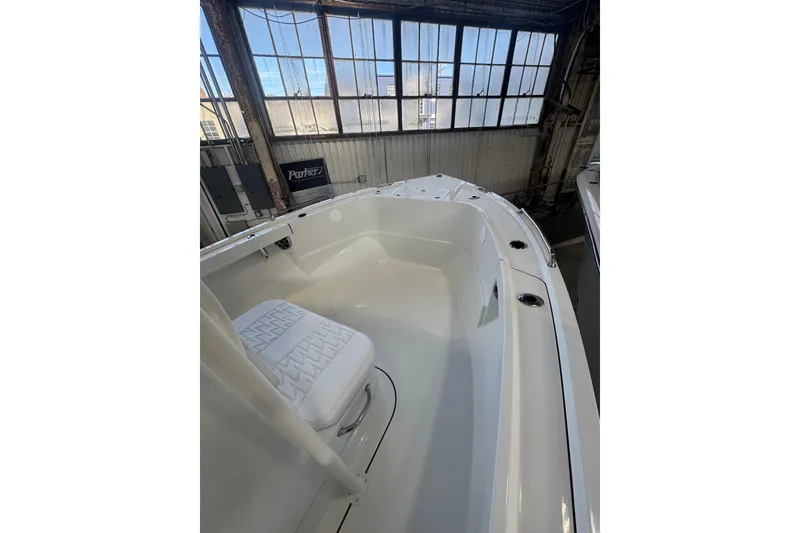 Slide: The Image of 2026 Parker 210 Coastal boat interior with white seating in a sunlit warehouse. - 10