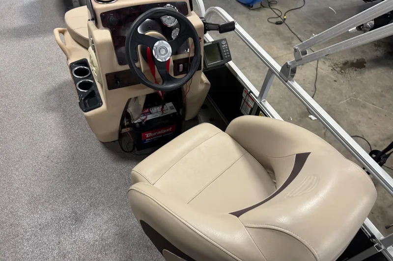 Slide: The Image of 2018 Sun Tracker Bass Buggy 18 DLX boat interior with steering wheel and beige seating. - 18
