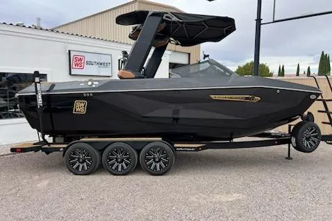 The Image of 2025 Nautique Super Air Nautique G23 boat on trailer, sleek black design, parked outdoors. - 1