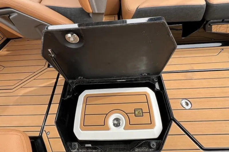 Slide: The Image of 2025 Nautique Super Air Nautique G23 storage compartment with open lid on teak deck. - 14