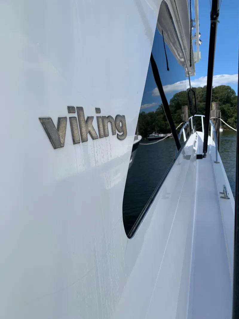 Slide: The Image of 2000 Viking 50 Convertible yacht, sleek design, docked by serene waters. - 11