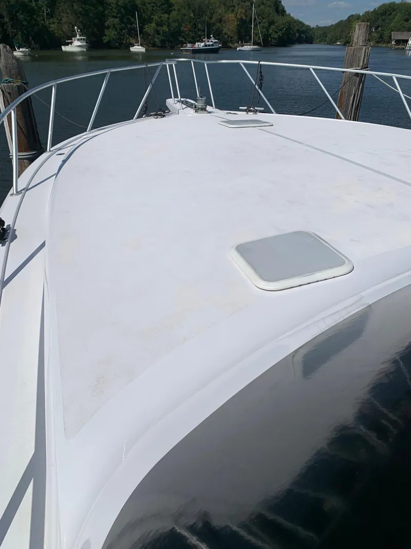Slide: The Image of 2000 Viking 50 Convertible yacht bow, docked on a serene river with lush greenery. - 15