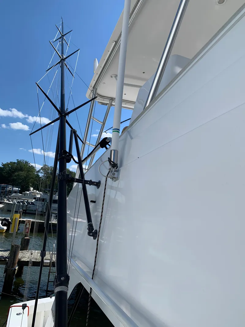 Slide: The Image of 2000 Viking 50 Convertible yacht, side view with fishing rods, docked under clear blue sky. - 18