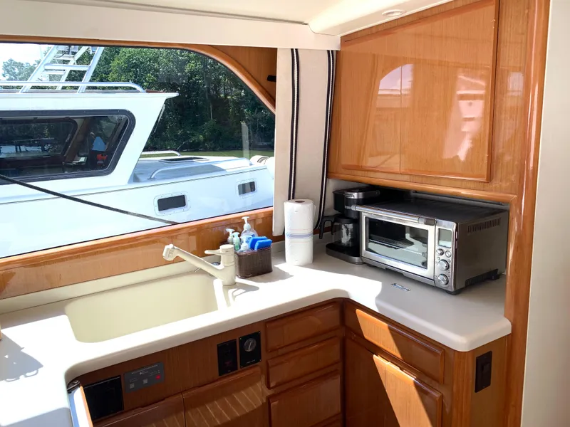 Slide: The Image of 2000 Viking 50 Convertible yacht kitchen with sink, microwave, and wooden cabinetry. - 24