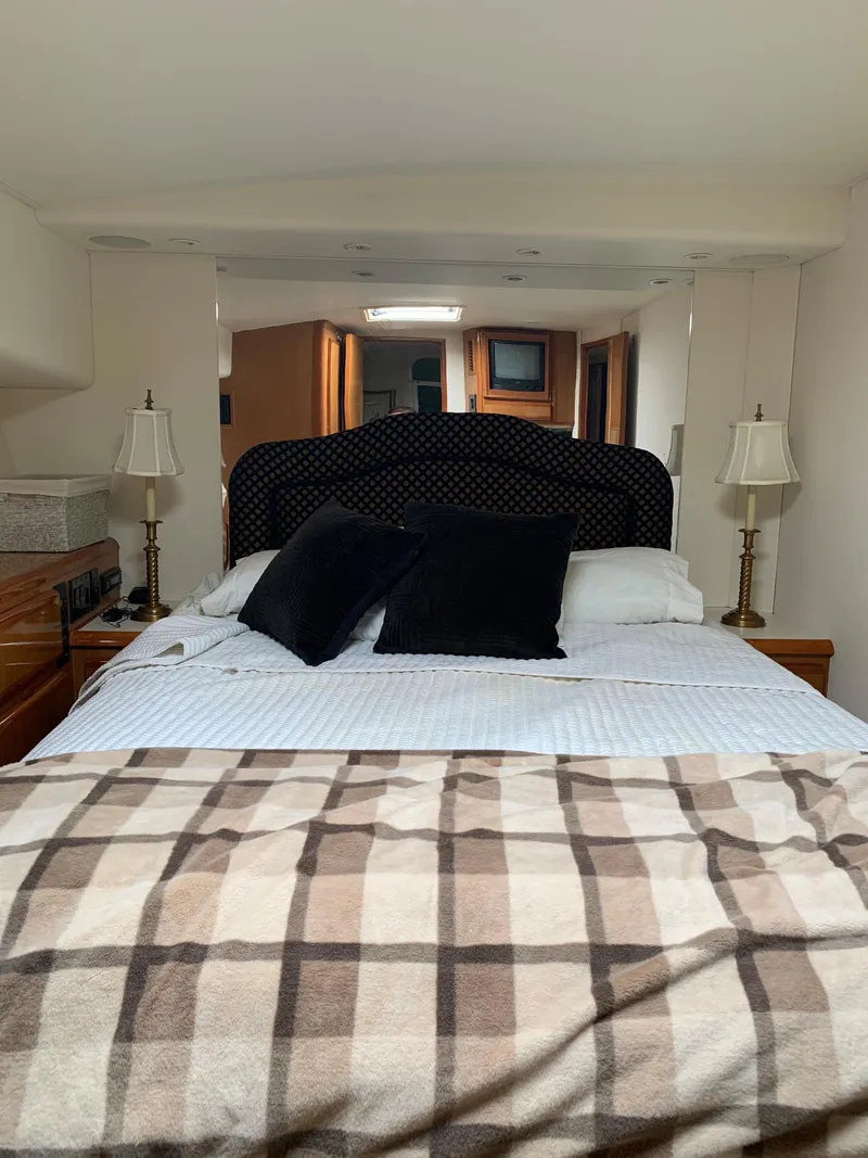 Slide: The Image of Interior of 2000 Viking 50 Convertible yacht bedroom with bed, lamps, and plaid blanket. - 30