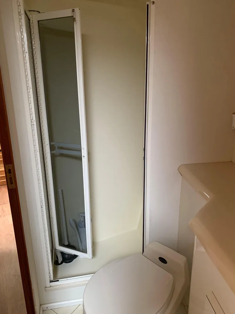 Slide: The Image of Bathroom interior of a 2000 Viking 50 Convertible yacht, featuring a compact shower and toilet. - 36