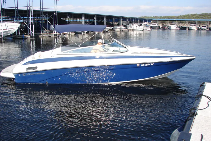 Slide: The Image of 2008 Crownline 270 BR boat docked in marina, blue and white design. - 0