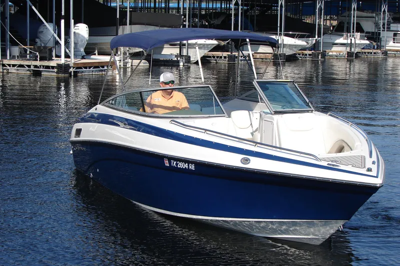 Slide: The Image of 2008 Crownline 270 BR boat with blue hull, docked in marina, featuring a canopy. - 10