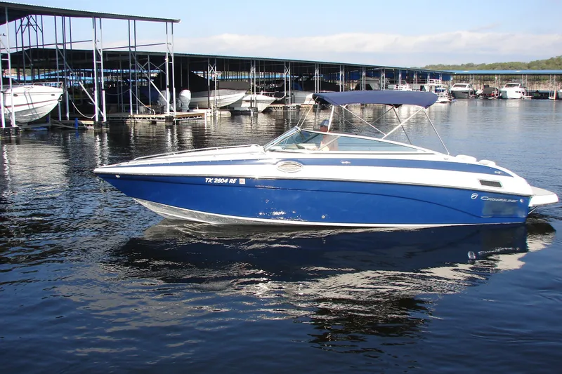 Slide: The Image of 2008 Crownline 270 BR boat docked in marina, featuring blue and white design. - 7